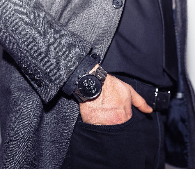 An arm in a white shirt with a large silver watch on the wrist