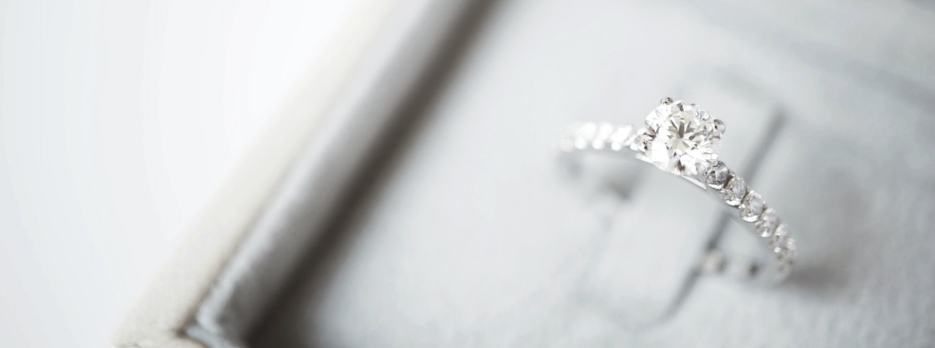 A silver jewelled engagement ring in a white box